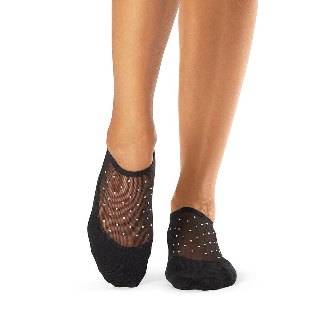 Black grip socks with white polka dots diamonds worn by a person on a white background