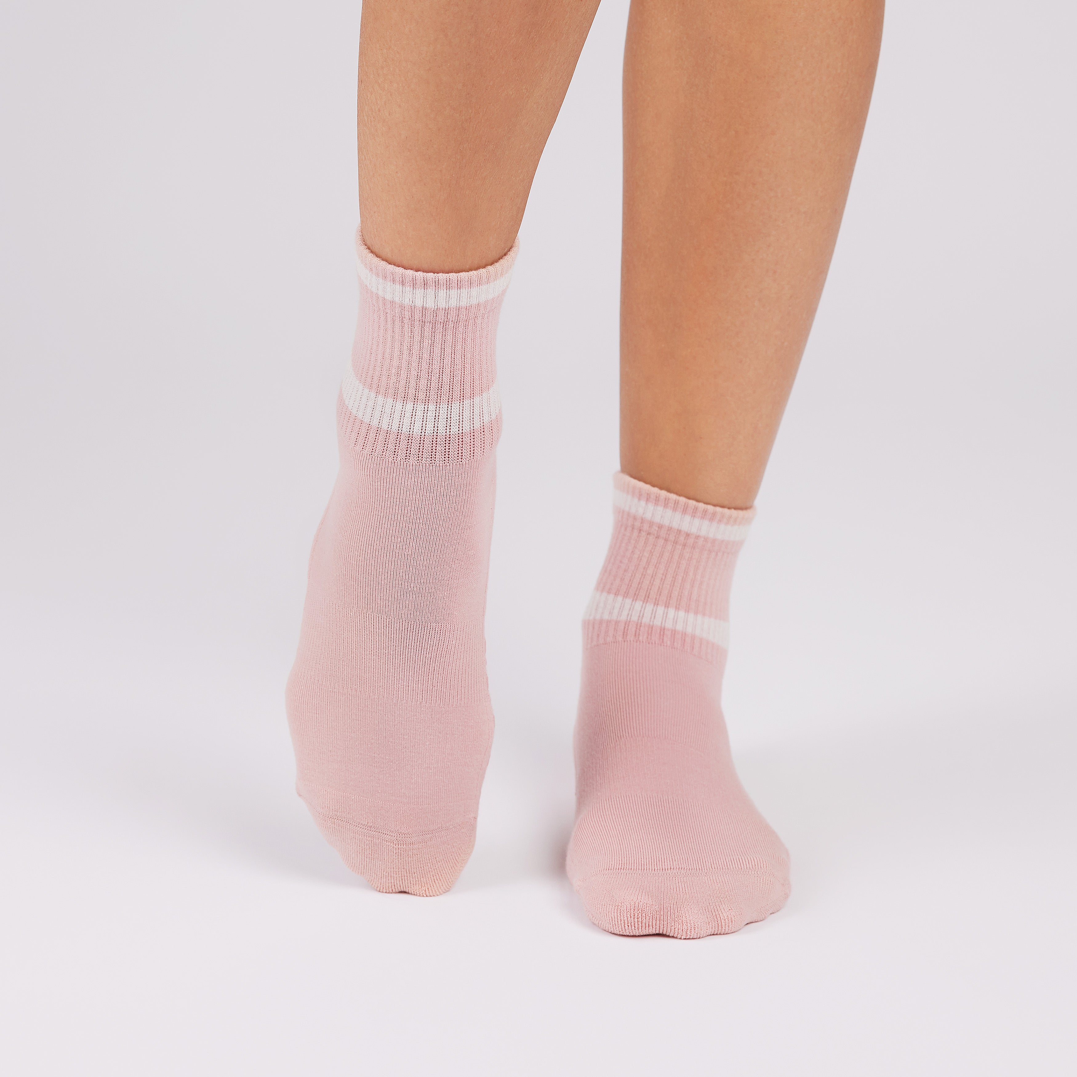 Pink socks with white stripes worn by a person on a light gray background