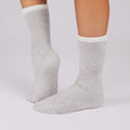 Gray fuzzy non slip sole socks with white cuffs on a light gray background