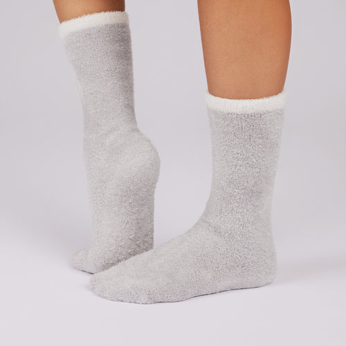 Gray fuzzy non slip sole socks with white cuffs on a light gray background