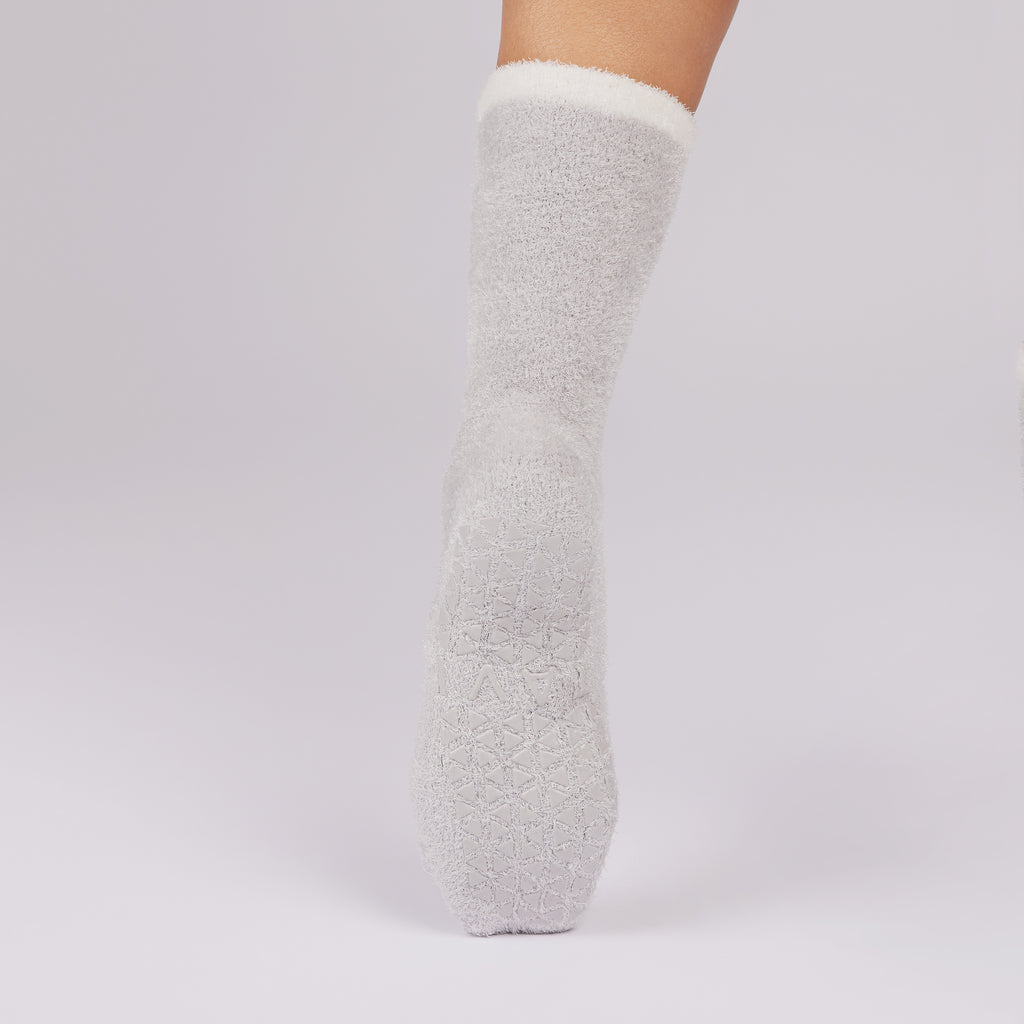 White fuzzy non slip sole sock on a light gray background