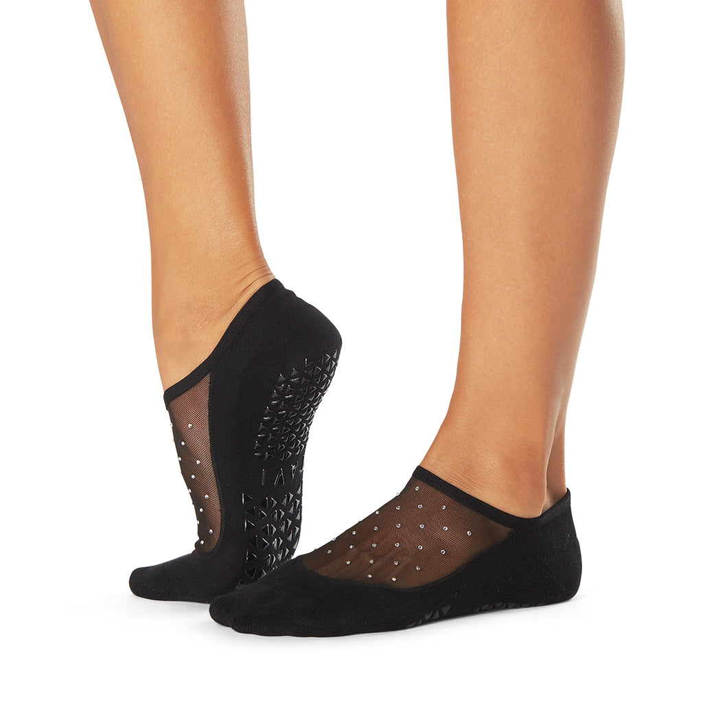 Black grip socks with white polka dots diamonds worn by a person on a white background