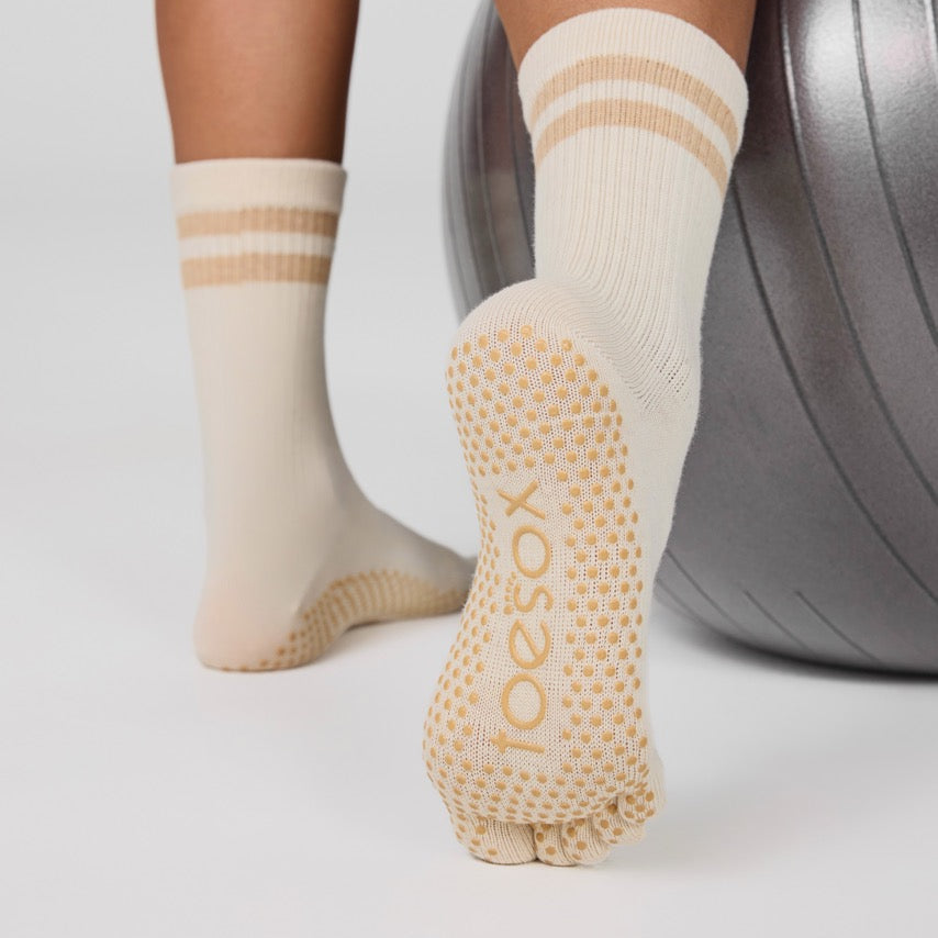 Person wearing beige grip socks with 'Joe Sox' branding, standing next to a silver dumbbell.