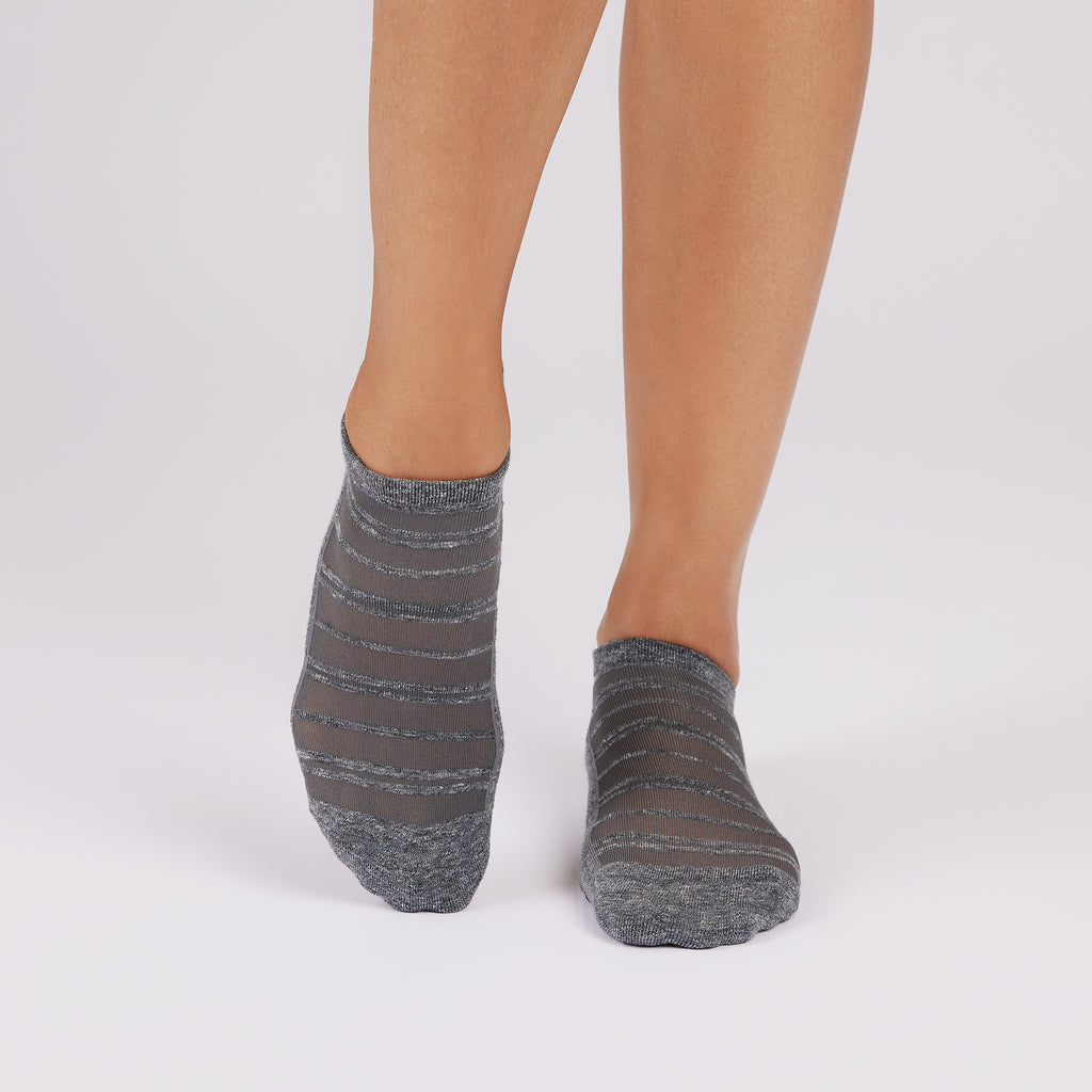 Gray striped mesh grip socks worn by a person on a white background