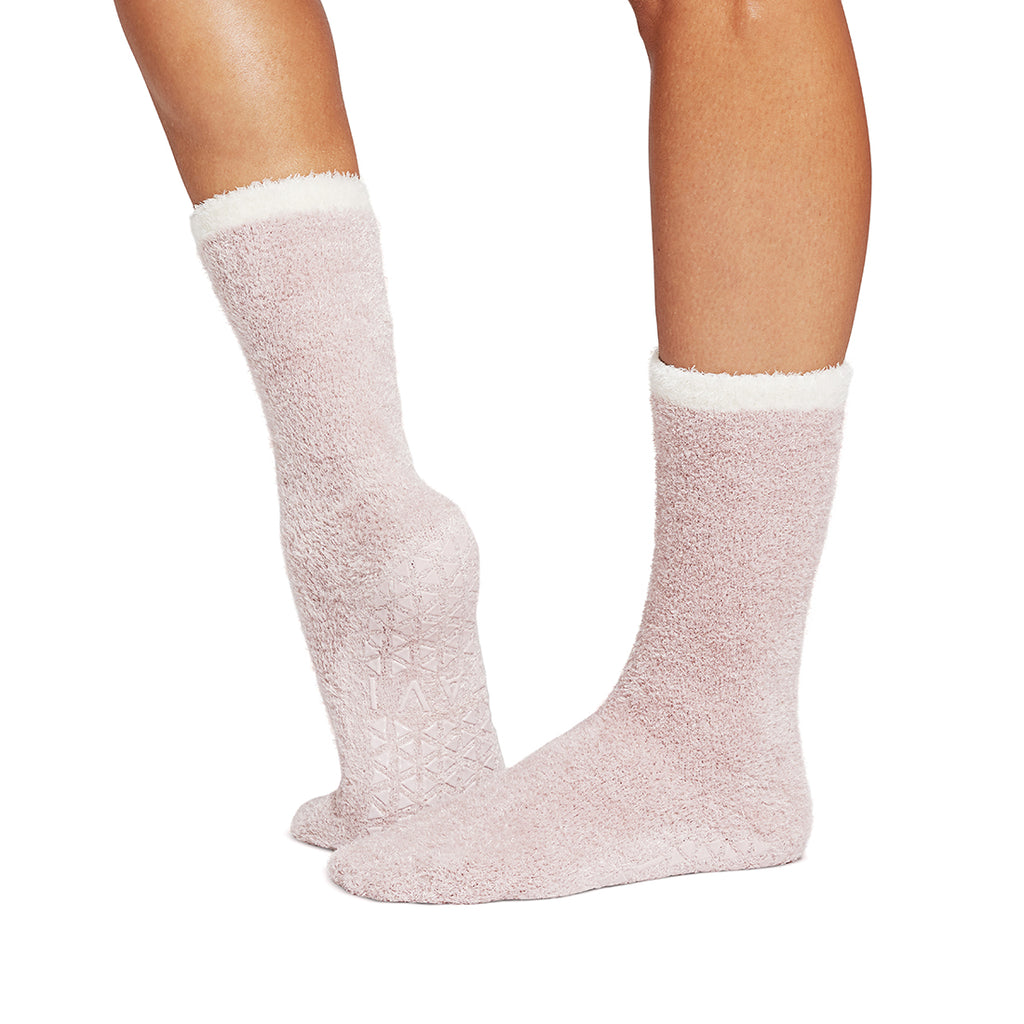 White fuzzy socks worn by a person on a white background