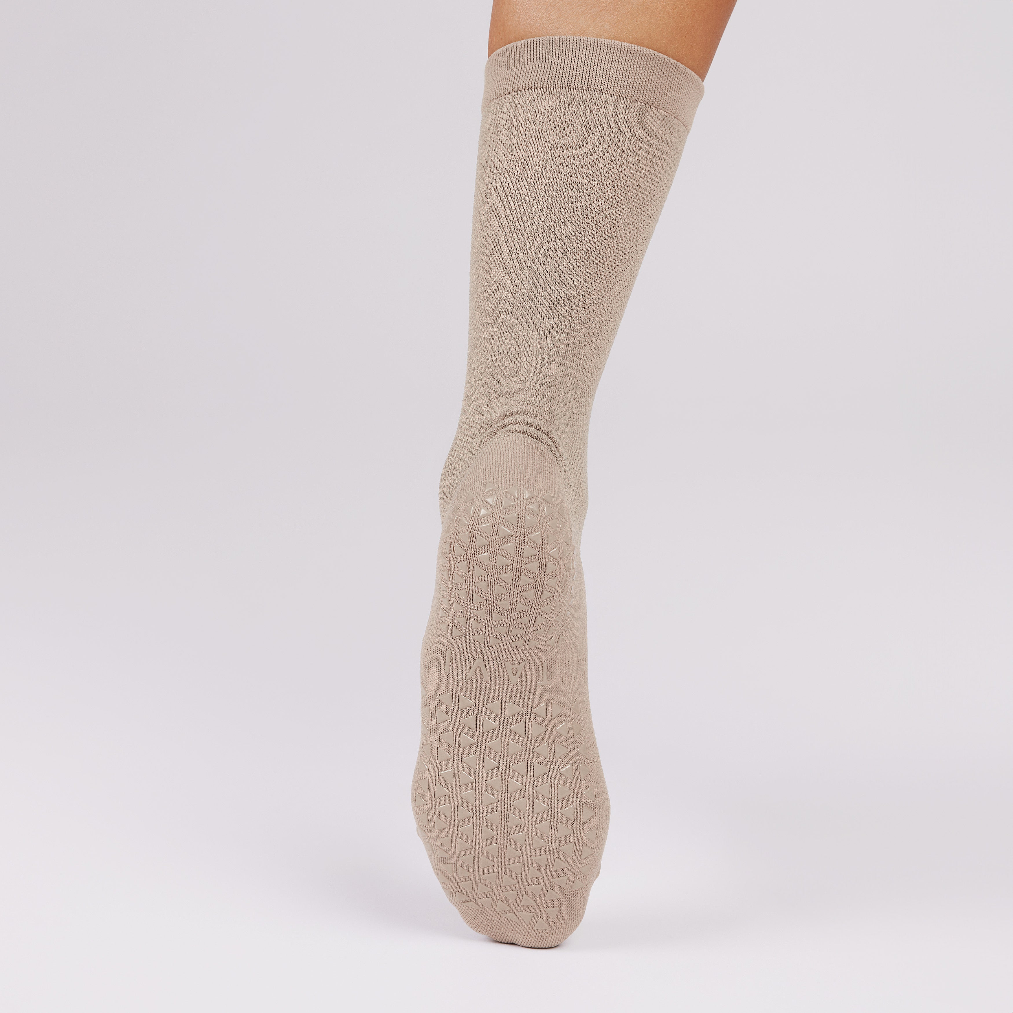 Beige sock with non slip sole on a light gray background