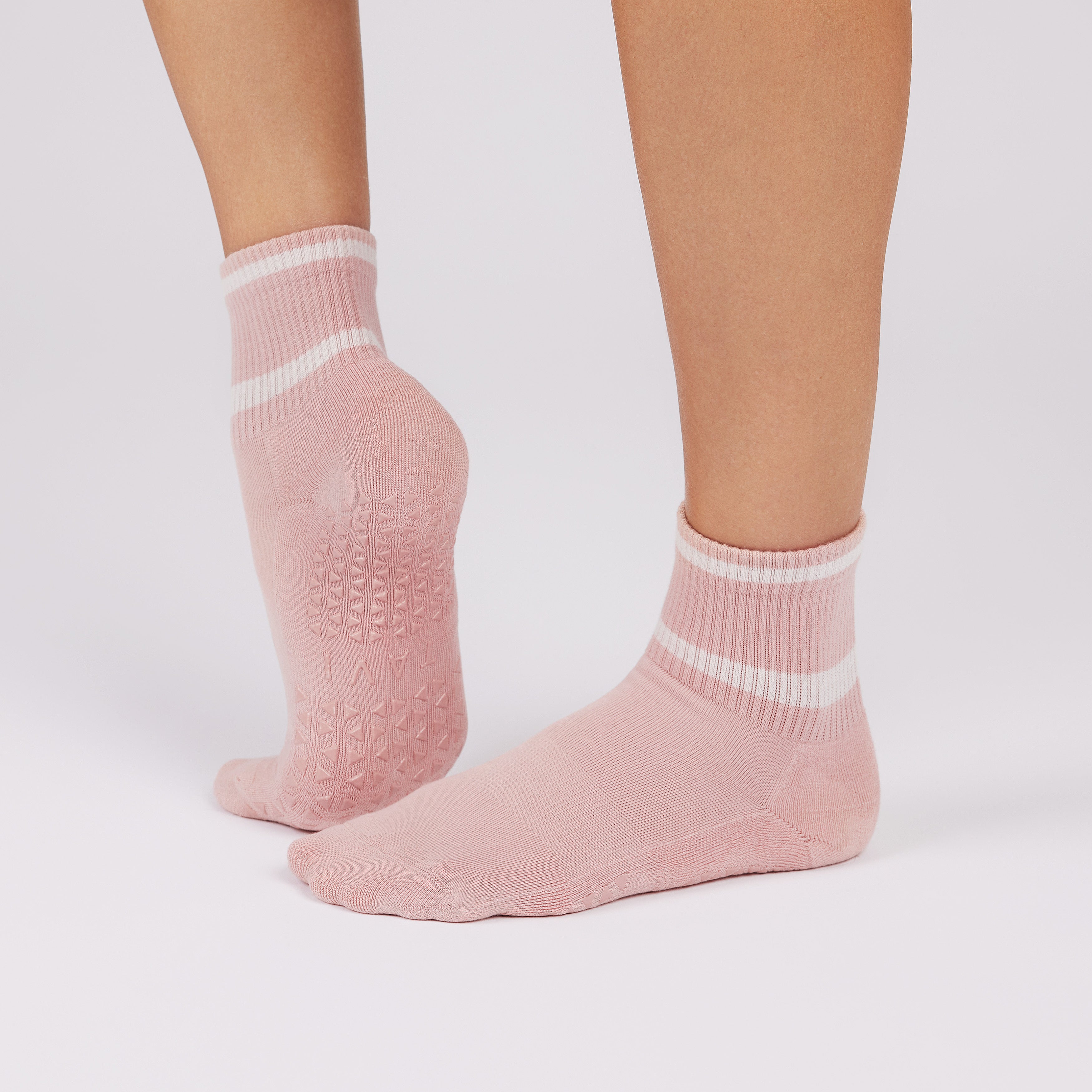 Pink socks with white stripes worn by a person on a light gray background